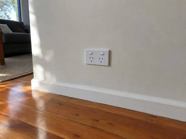 Double power point on a cream wall above white skirting in a timber-floored living room in Morisset
